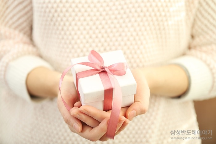 분홍 리본으로 잘 묶인 선물 박스를 들고 있는 남자