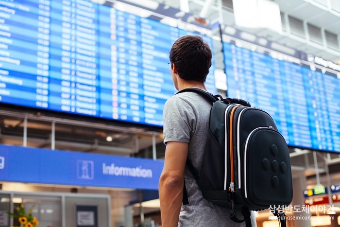 공항 안내판 앞에서 배낭을 멘 여행객