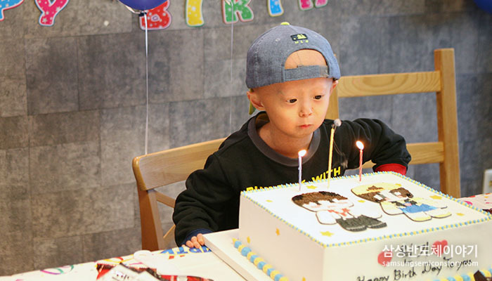 생일 케이크의 촛불을 끄는 아이