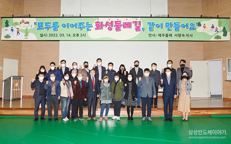 '모두를 이어주는 화성둘레길, 같이 만들어요' 일사 : 2022년 3월 14일 오후 2시 연사 : 제주올레 서명숙 이사. 체육관 앞에서 같은 포즈를 취한 채 단체사진을 찍고 있는 모습